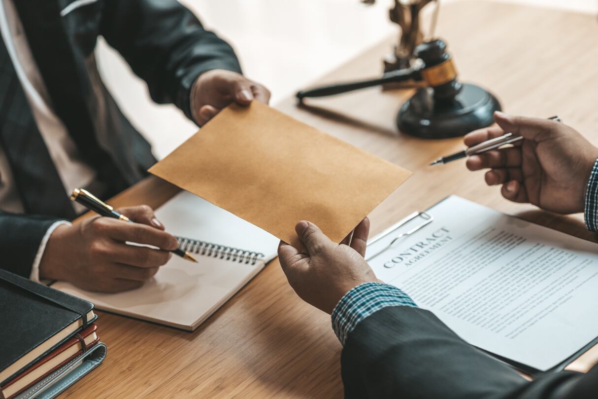 A lawyer handing a document to a colleague.