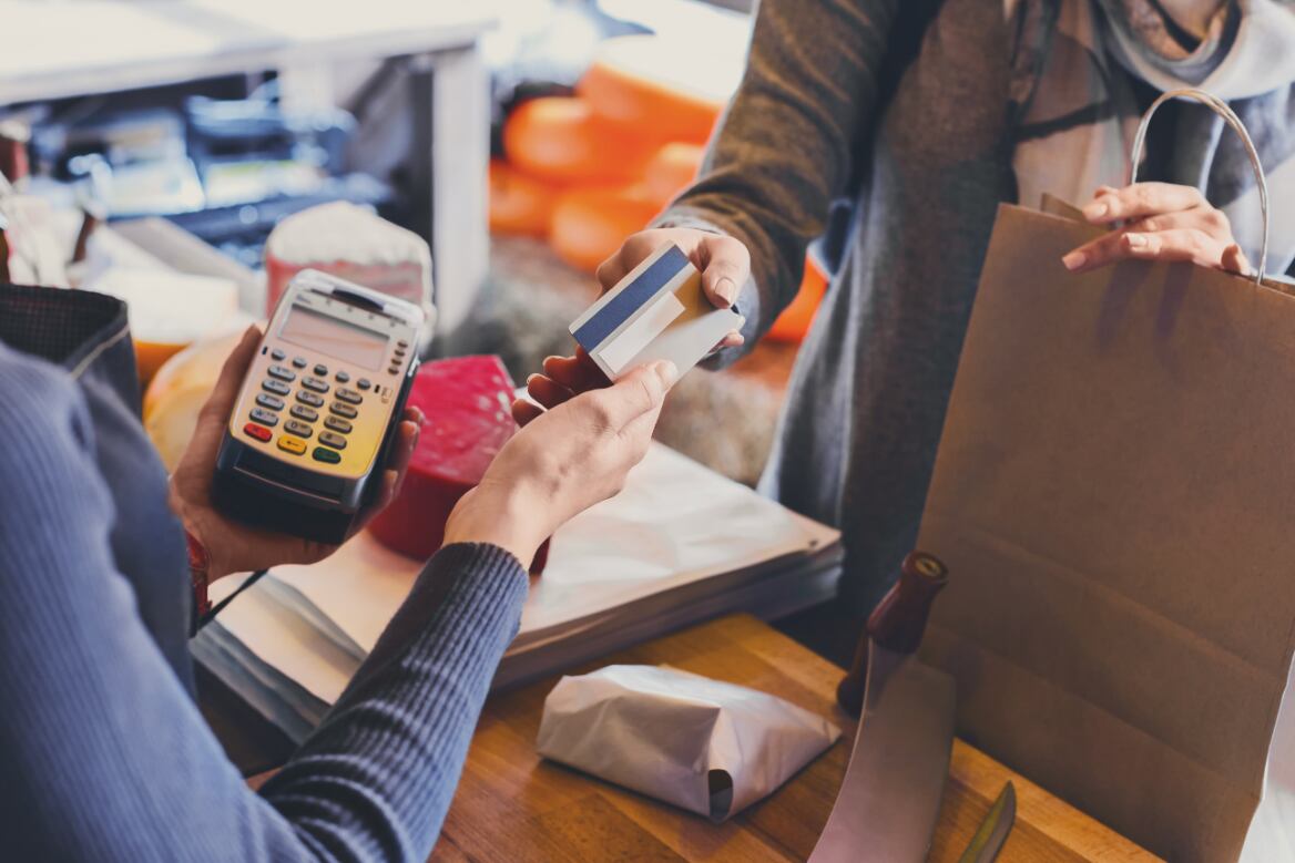 A woman purchasing something at the register at a store. 